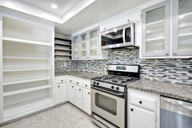 a kitchen with granite countertop a stove microwave and sink