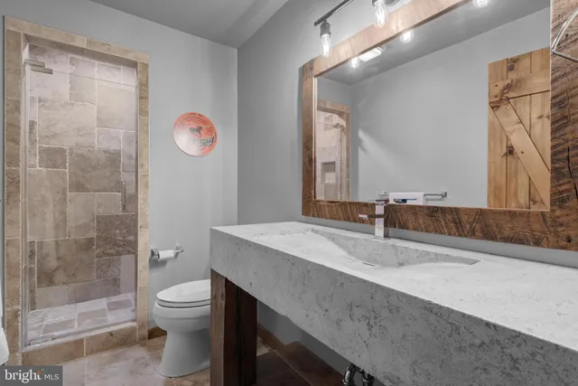 a bathroom with a sink a toilet a mirror and shower