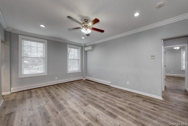 724 Howell Avenue, Unit E Riverhead, NY 11901 - Photo 4 of 10 an empty room with wooden floor fan and windows