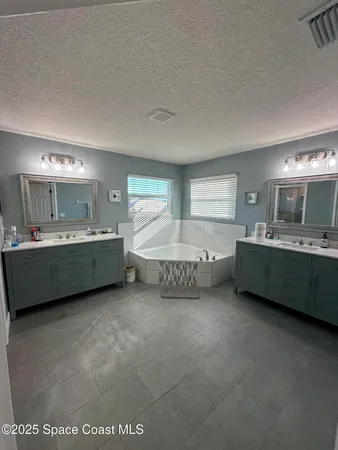 a bathroom with a double vanity sink mirror and bathtub