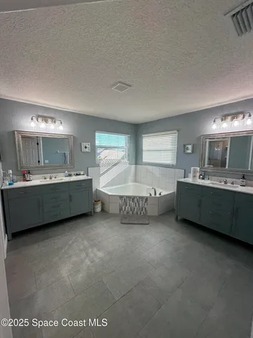 a bathroom with a double vanity sink mirror and bathtub