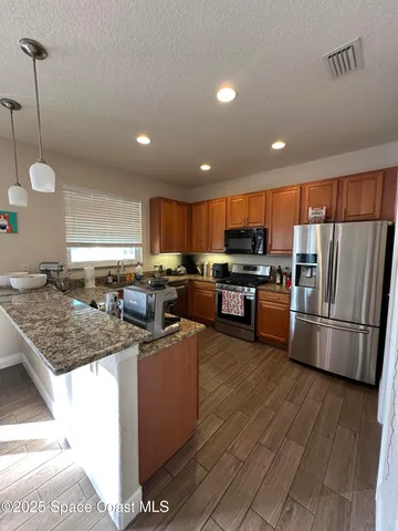 a kitchen with stainless steel appliances granite countertop a stove a sink dishwasher a refrigerator and a oven with wooden floor