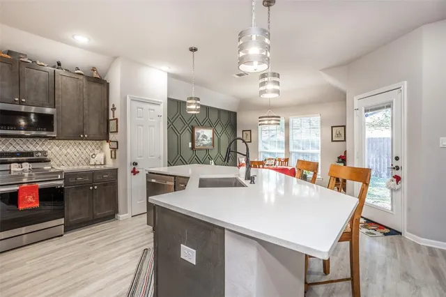 a large kitchen with kitchen island a stove a sink a refrigerator and a dining table with wooden floor