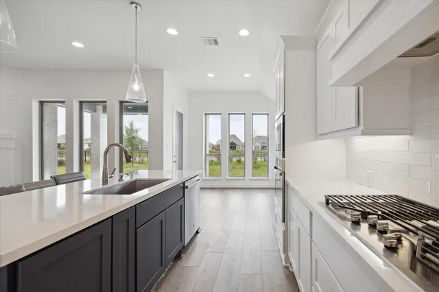 a kitchen with stainless steel appliances granite countertop a sink a stove and a wooden floors