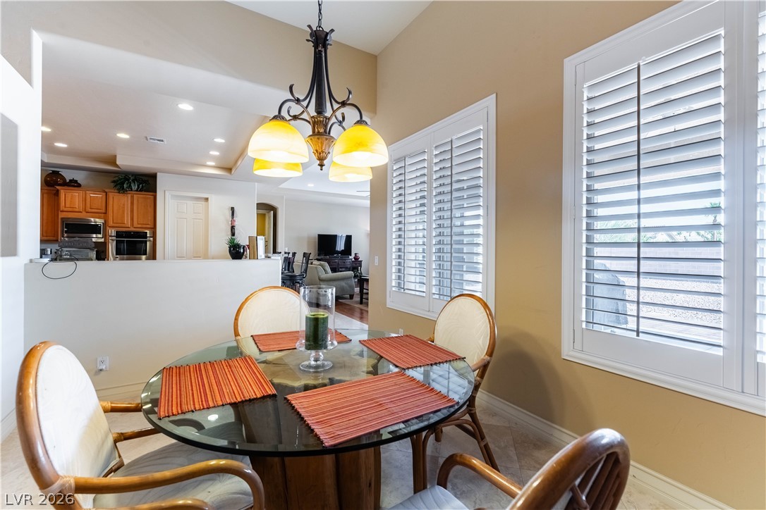 3661 Riley Ann Avenue Las Vegas, NV 89139 - Photo 18 of 42 A graceful chandelier illuminates the informal dining space, featuring classic plantation shutters.