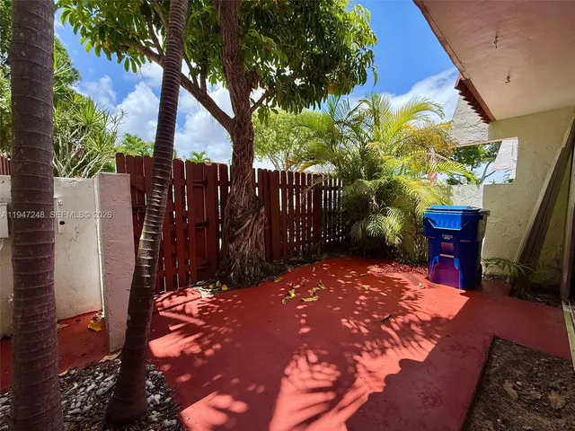 a view of backyard with wooden fence and trees