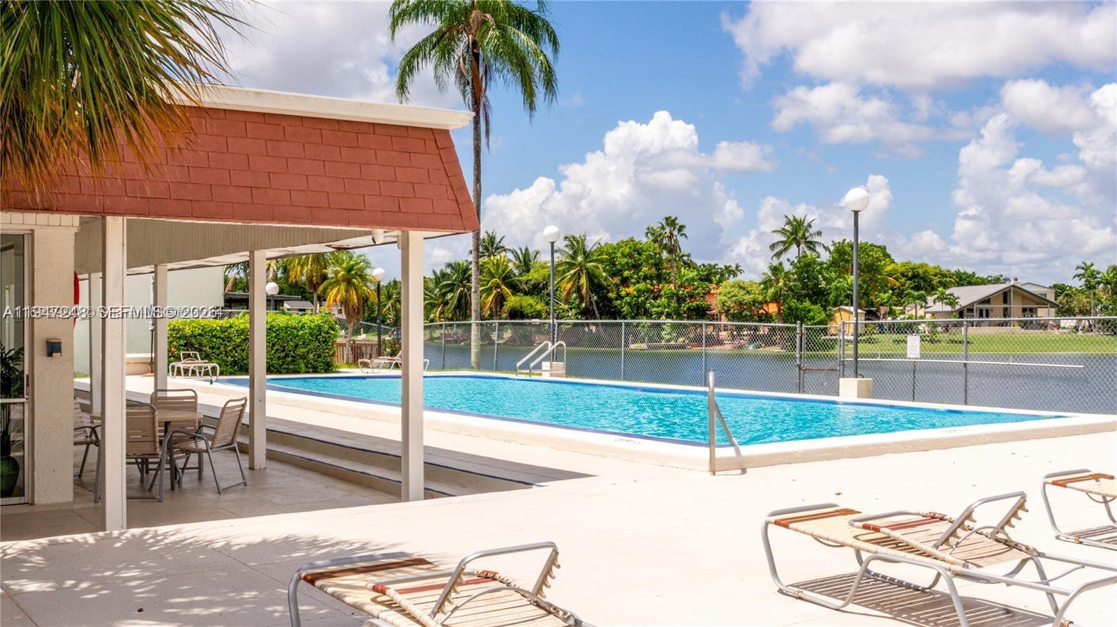 13935 Southwest 84th Street, Unit 905 Miami, FL 33183 - Photo 28 of 33 a view of a swimming pool with a lawn chairs under an umbrella