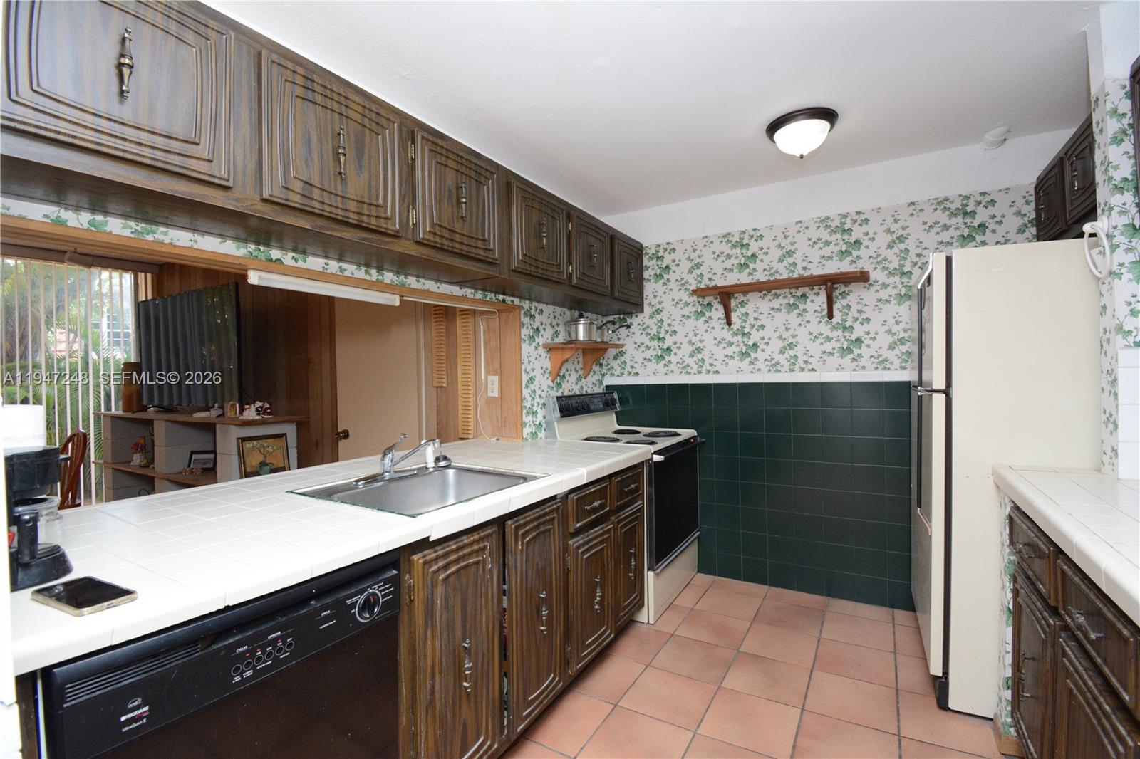 13935 Southwest 84th Street, Unit 905 Miami, FL 33183 - Photo 10 of 33 a kitchen with a sink refrigerator and cabinets