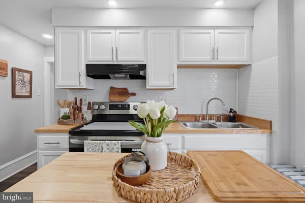 a kitchen with stainless steel appliances granite countertop a refrigerator a stove a sink dishwasher a dining table and chairs with wooden floor