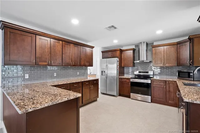 a kitchen with stainless steel appliances granite countertop refrigerator sink stove microwave and cabinets