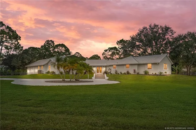 a front view of a house with a garden and trees