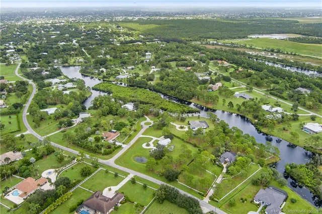 an aerial view of a residential houses with outdoor space and a lake view
