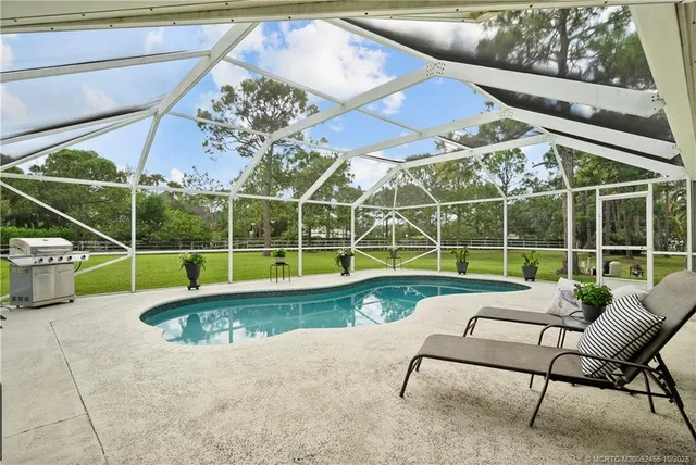 a view of a swimming pool with a patio and a yard