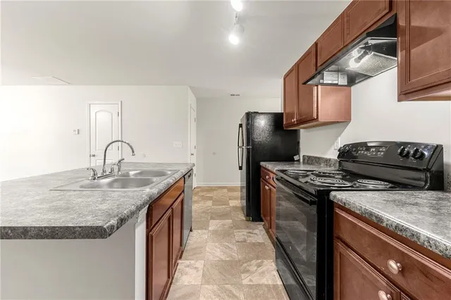 a kitchen with granite countertop a sink stove and refrigerator
