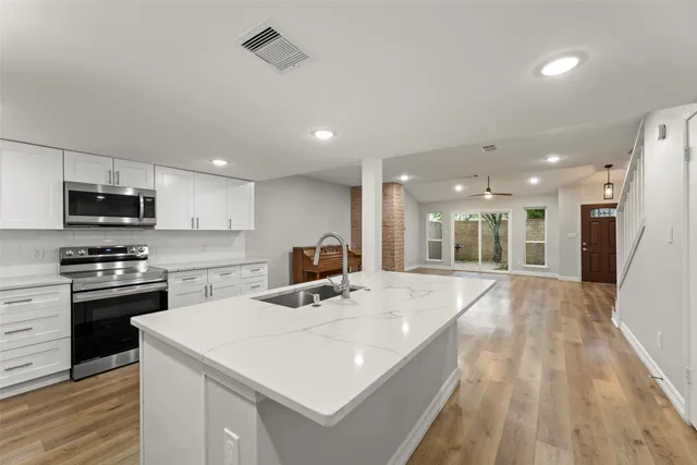 a large kitchen with stainless steel appliances kitchen island a stove a refrigerator a oven a sink with island and chairs