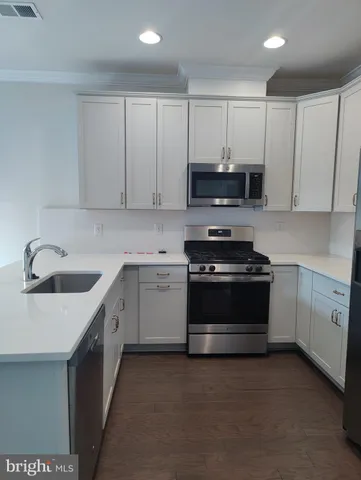 a kitchen with granite countertop white cabinets and stainless steel appliances