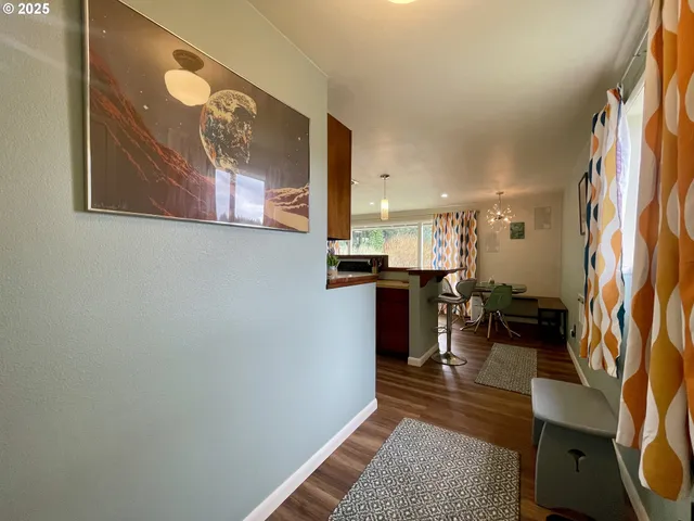 a open kitchen with stainless steel appliances granite countertop a stove top oven a dining table and chairs with wooden floor