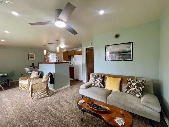 a living room with furniture a flat screen tv and kitchen view