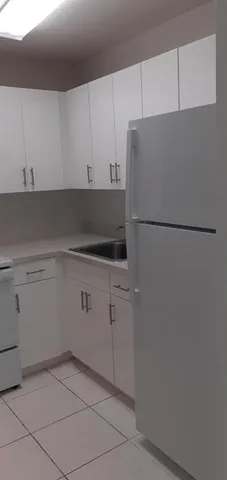 a view of kitchen with granite countertop white cabinets and a sink
