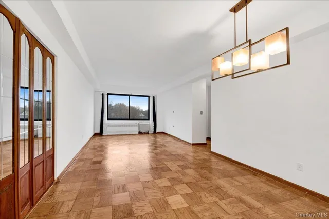 a view of an empty room with wooden floor and windows