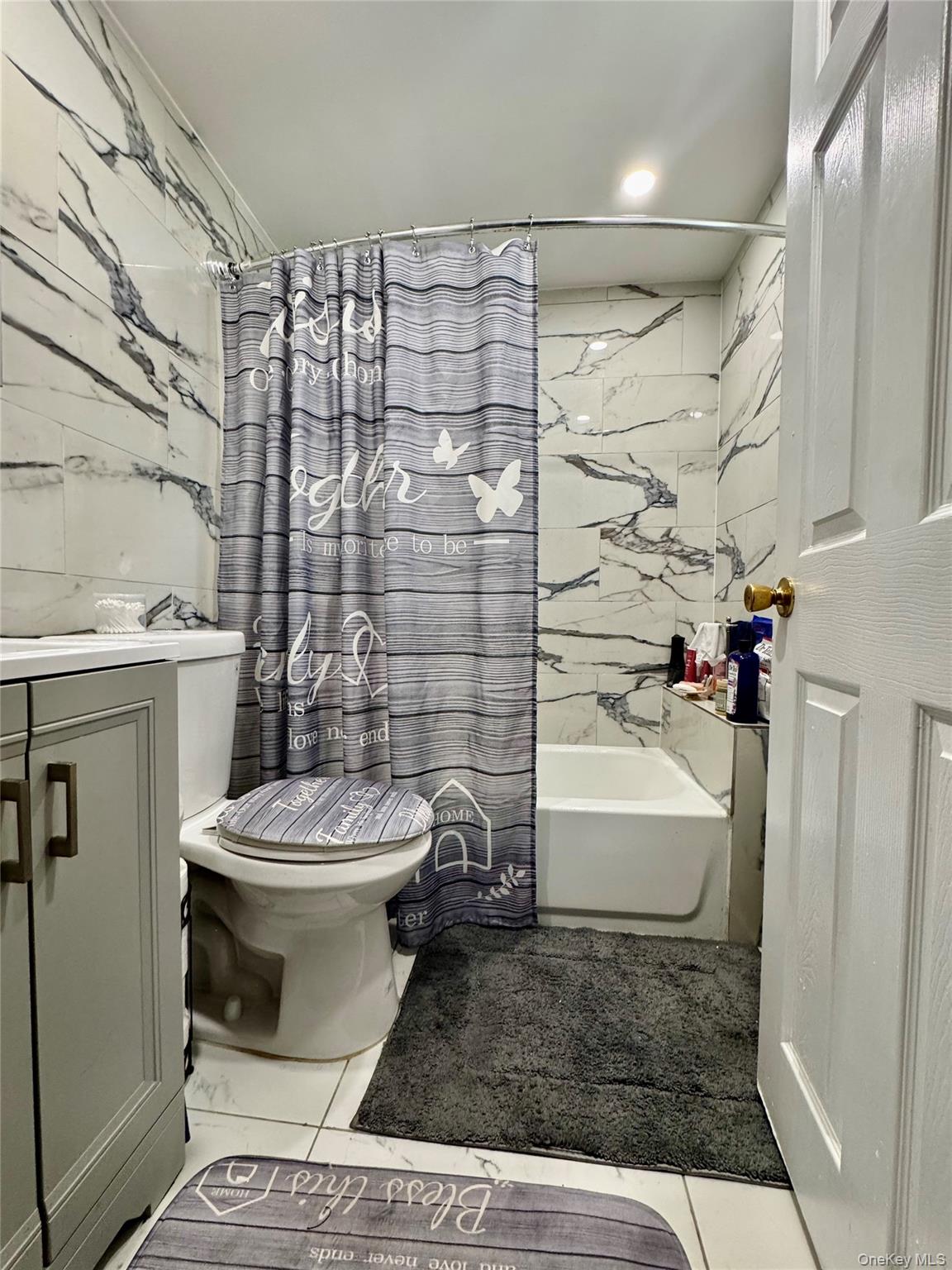 188-25 Mangin Avenue Queens, NY 11412 - Photo 5 of 10 Bathroom featuring tile walls, shower / bathtub combination with curtain, and vanity