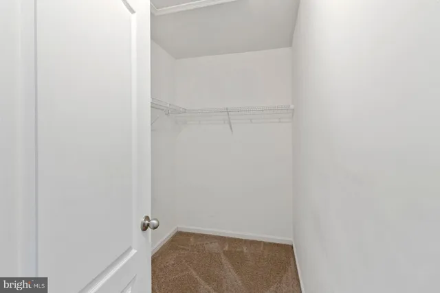 an empty room with a chandelier fan and closet area