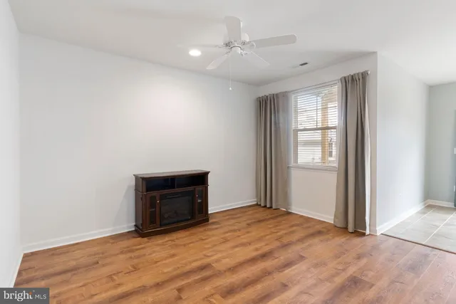 an empty room with wooden floor fireplace and windows
