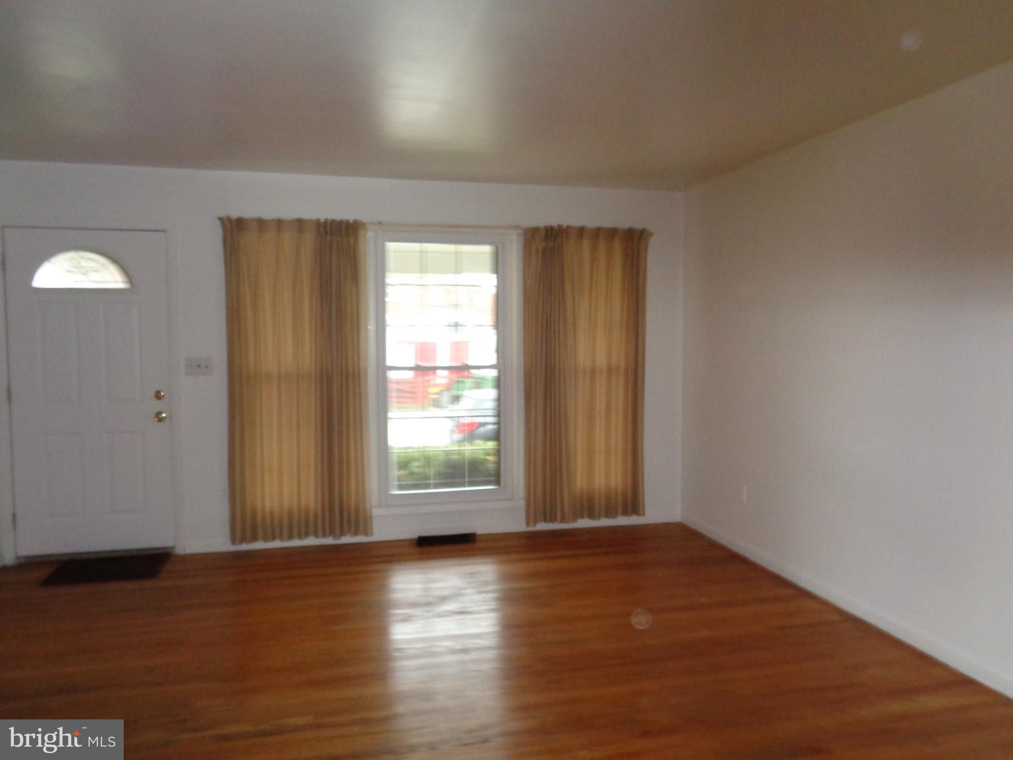 6213 Marlora Road Baltimore, MD 21239 - Photo 2 of 26 an empty room with wooden floor and windows