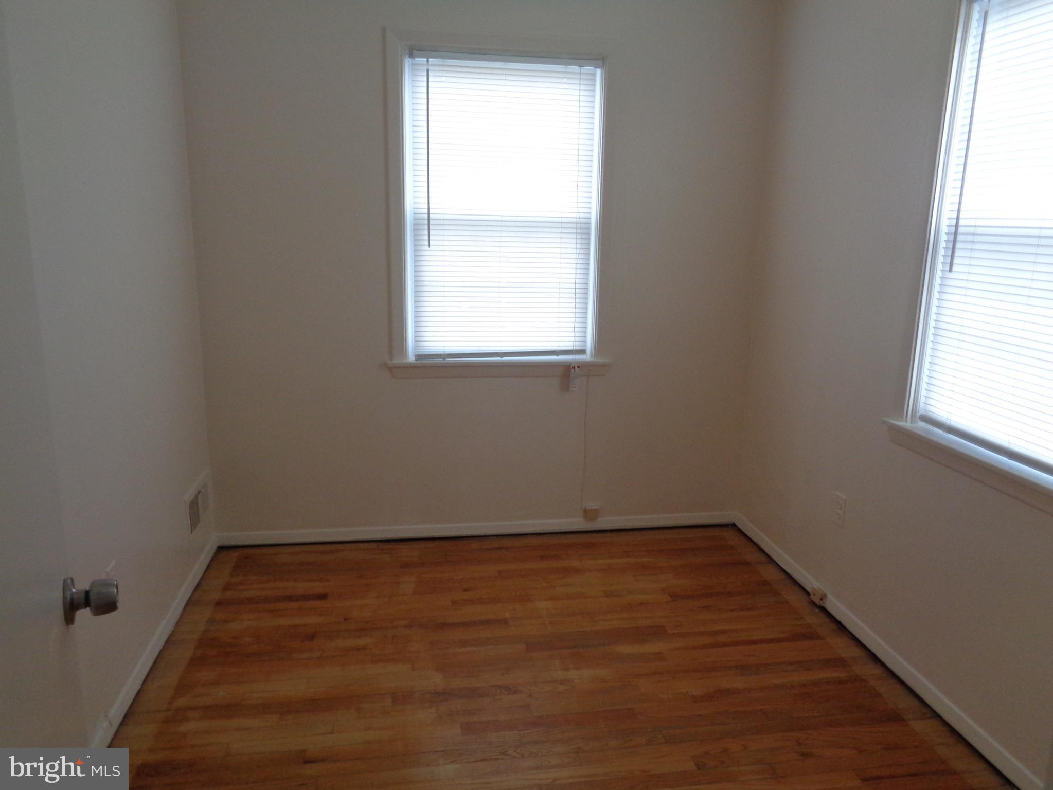 6213 Marlora Road Baltimore, MD 21239 - Photo 11 of 26 an empty room with wooden floor and windows
