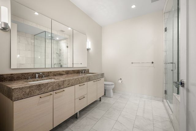a bathroom with a granite countertop sink a toilet and shower