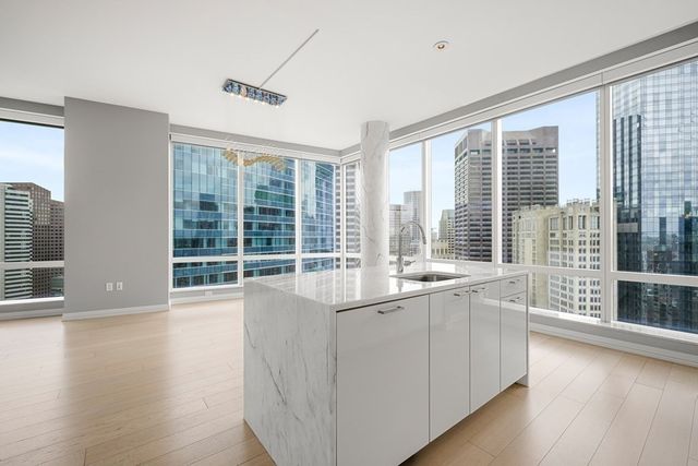 a large white kitchen with wooden floor and a large window
