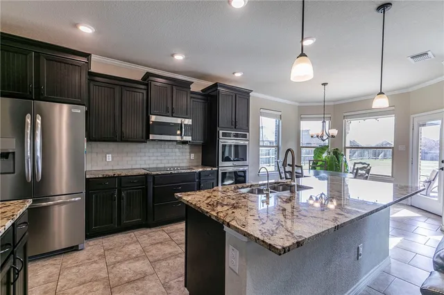 a kitchen with stainless steel appliances granite countertop a sink refrigerator and microwave