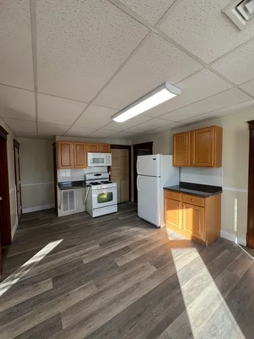a room with stainless steel appliances kitchen island granite countertop a refrigerator a stove and a sink with cabinets