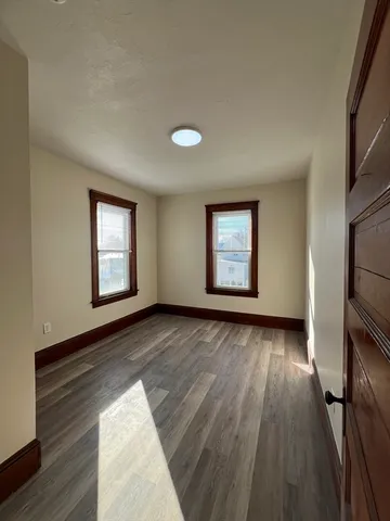 an empty room with wooden floor fireplace and windows