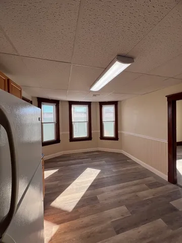 a view of an empty room with window and wooden floor