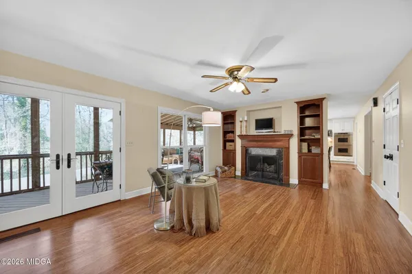 a view of a livingroom with furniture a fireplace wooden floor and windows