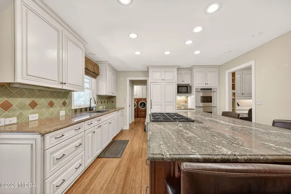 a large kitchen with granite countertop a large counter top stainless steel appliances and cabinets