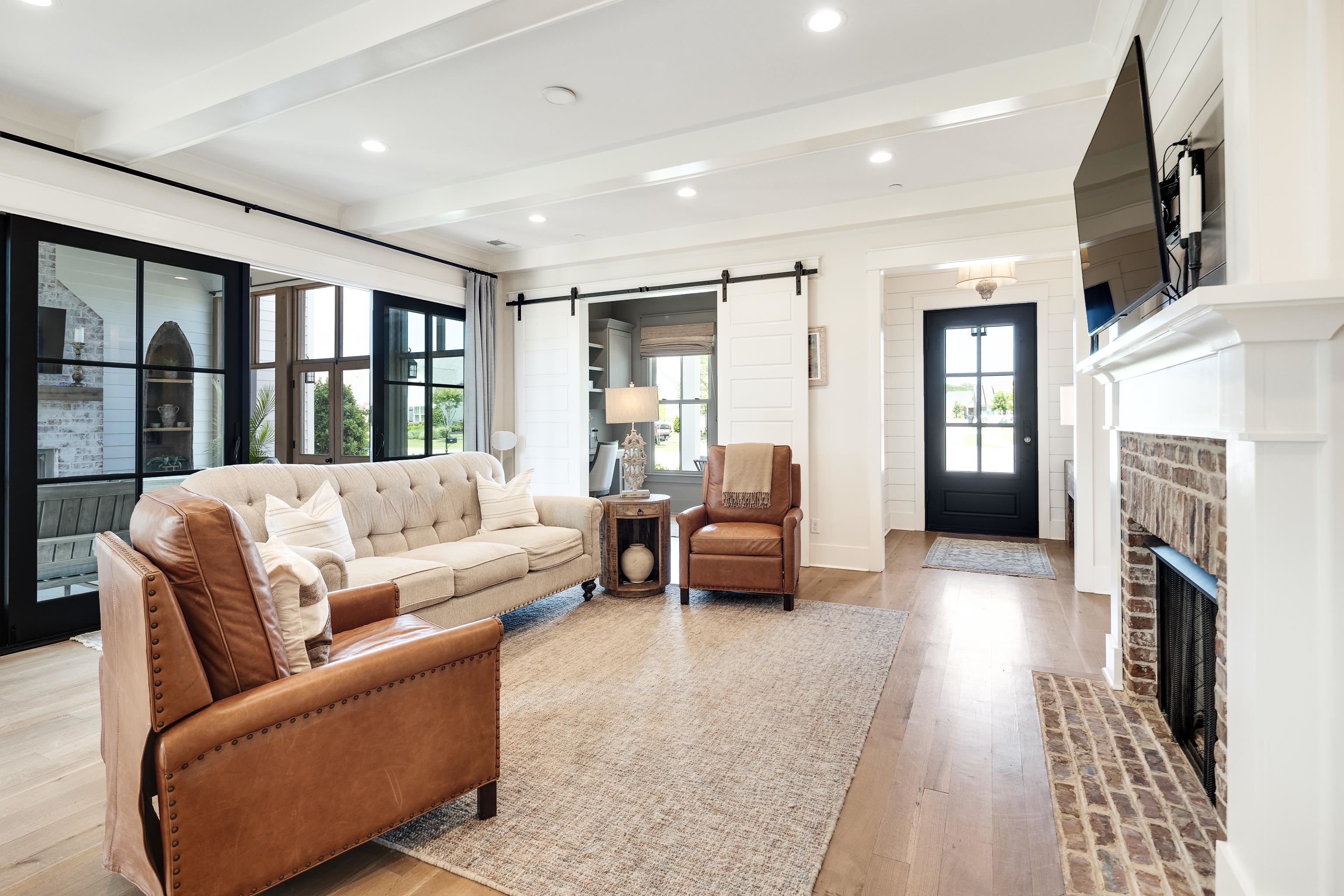 100 Sunflower View Road Piperton, TN 38017 - Photo 6 of 29 Spacious living area featuring wood-finish flooring, a brick fireplace with a white mantel, exposed beam ceiling accents, and recessed lighting