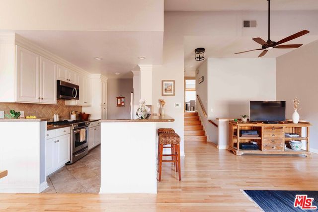 a living room with stainless steel appliances furniture and a flat screen tv