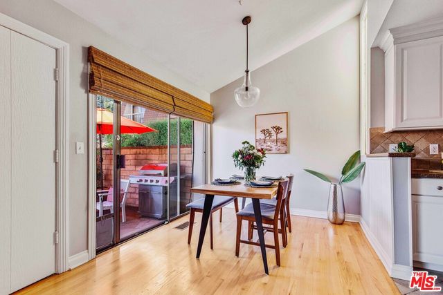 a view of a dining room with furniture one side kitchen view and wooden floor