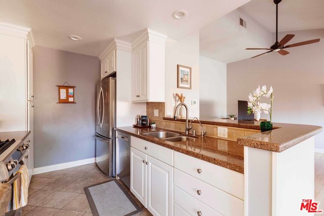 a kitchen with stainless steel appliances granite countertop a sink and a refrigerator