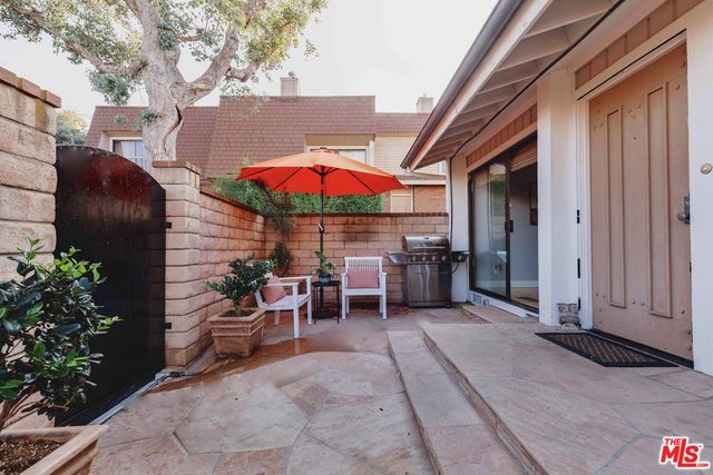 a view of a patio with a table and chairs under an umbrella