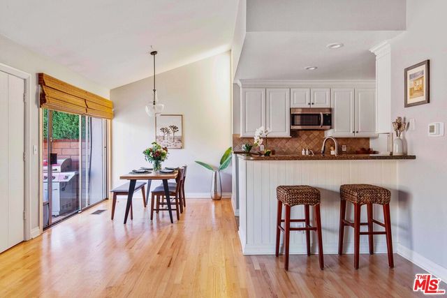 a kitchen with stainless steel appliances granite countertop a table chairs a sink a refrigerator and microwave