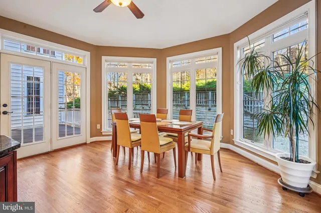 a living room with stainless steel appliances granite countertop a refrigerator a sink dishwasher a dining table and chairs with wooden floor