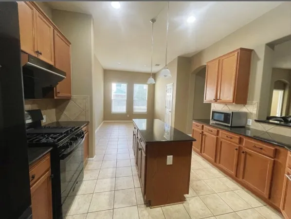 a kitchen with a refrigerator a microwave a sink and chairs