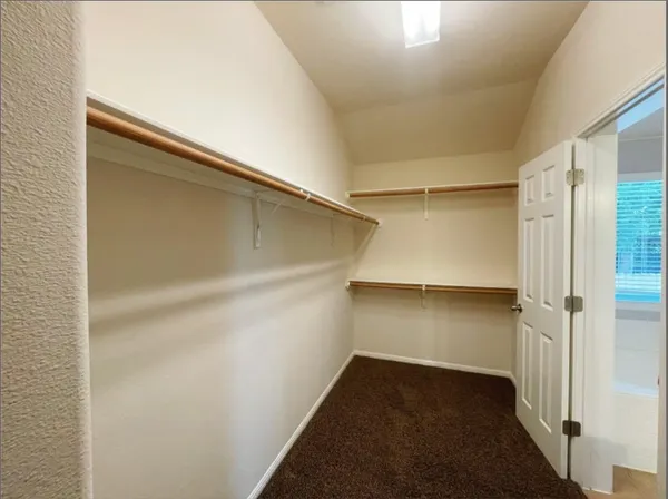 a view of an empty room and chandelier fan