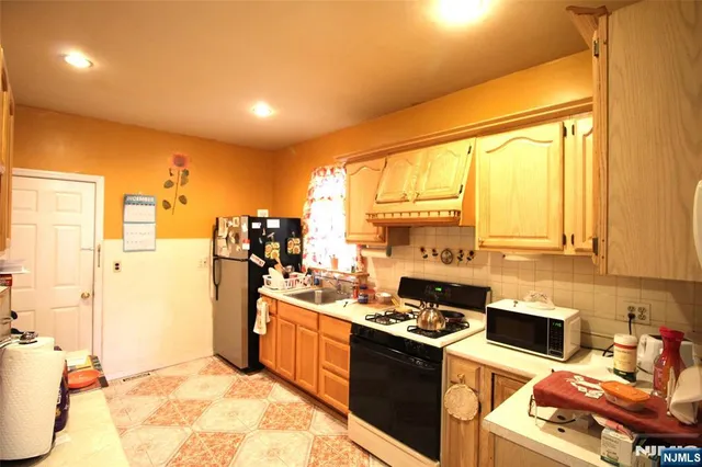 a kitchen with a sink appliances cabinets and a large window