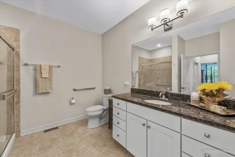 a bathroom with a granite countertop double vanity sink a mirror and a toilet
