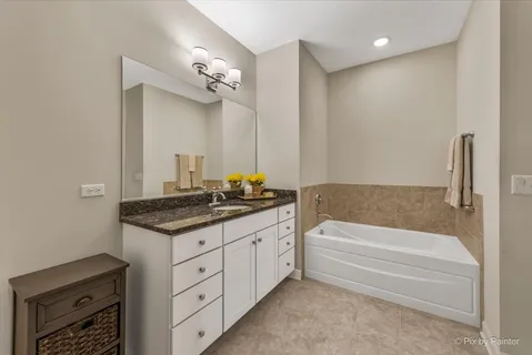 a bathroom with a granite countertop sink a toilet a mirror and bathtub