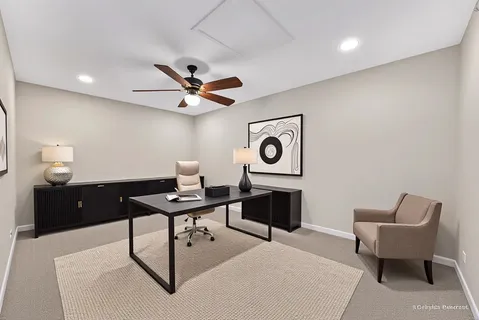 a work room with furniture a rug and a ceiling fan
